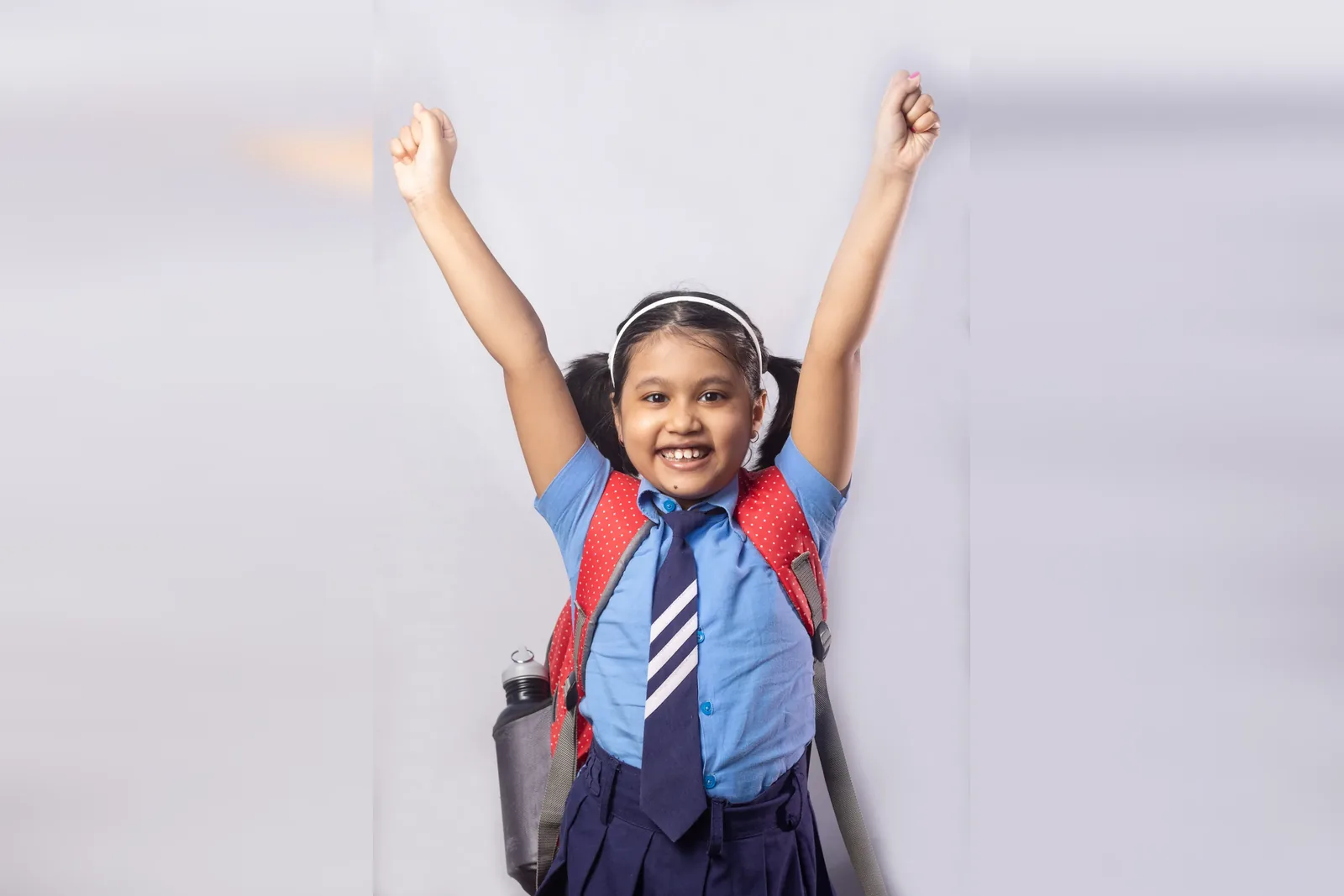 A schoolgirl in uniform raises both arms